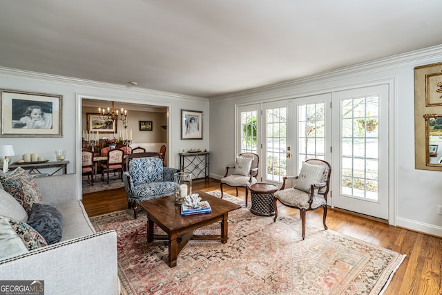 living room featuring wood-type flooring, an inviting chandelier, and crown molding