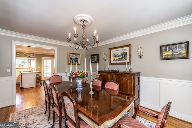 dining room with a chandelier, sink, light hardwood / wood-style floors, and ornamental molding