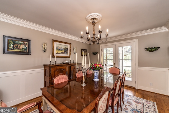 dining room with a chandelier, french doors, ornamental molding, and hardwood / wood-style flooring