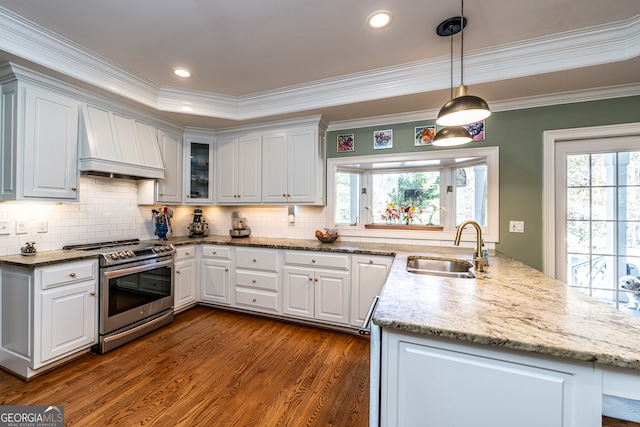 kitchen featuring gas range, white cabinetry, sink, hanging light fixtures, and premium range hood