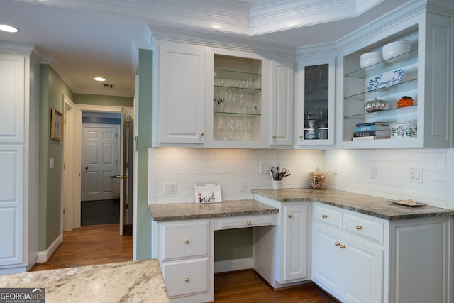 kitchen with light stone countertops, dark hardwood / wood-style flooring, white cabinetry, and ornamental molding