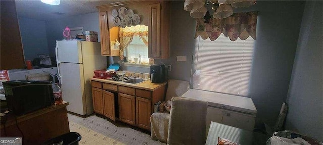 1556 Wellworth Ave, Macon, GA 31204 - kitchen with freestanding refrigerator, a sink, brown cabinets, light countertops, and light floors