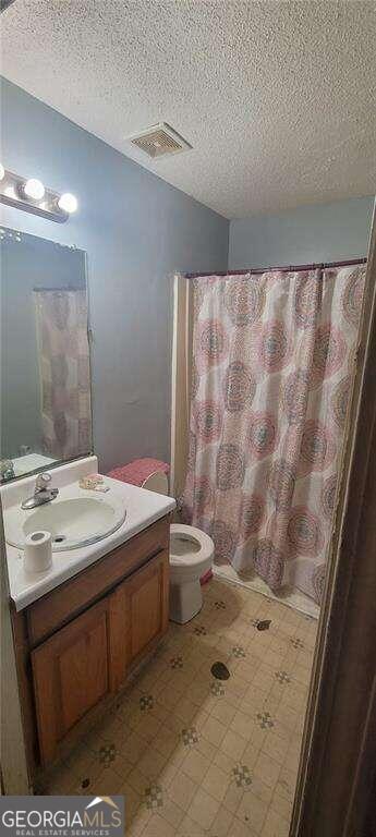 bathroom with vanity, toilet, a textured ceiling, and a shower with shower curtain