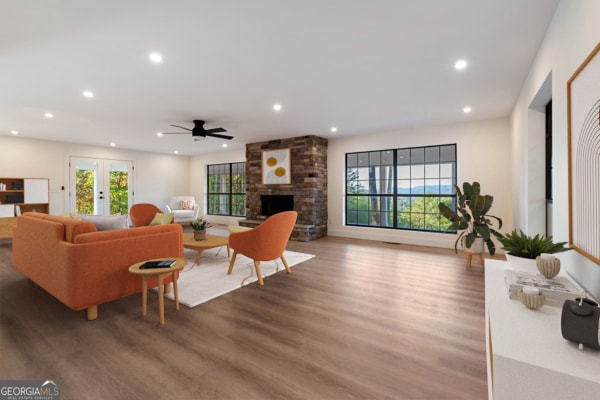 living room featuring hardwood / wood-style floors, a stone fireplace, french doors, and ceiling fan