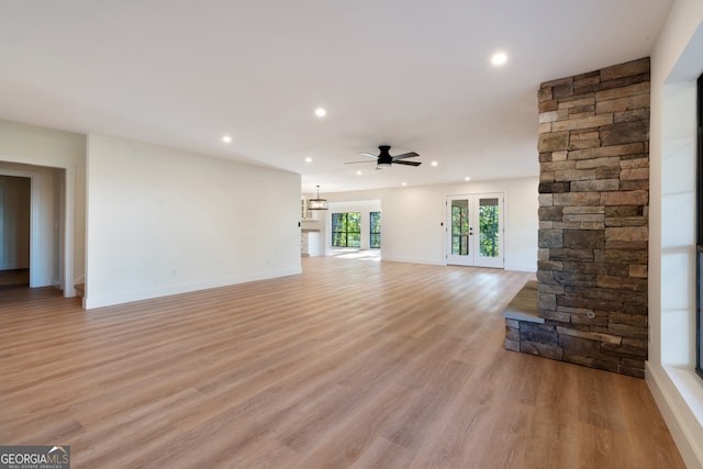 unfurnished living room with french doors, light wood-type flooring, and ceiling fan