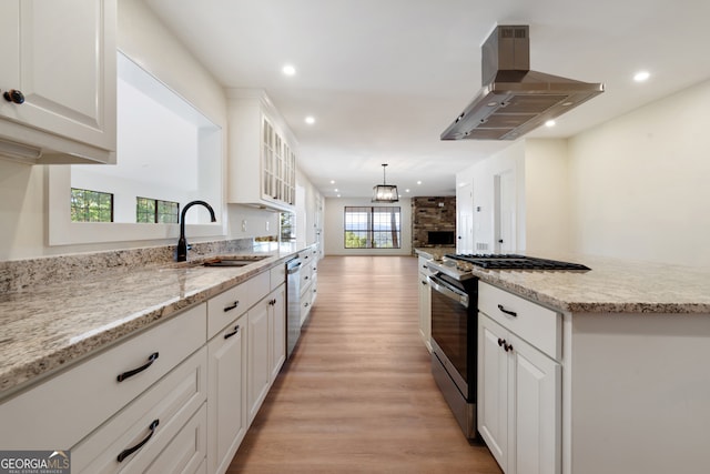 kitchen with island range hood, sink, white cabinetry, appliances with stainless steel finishes, and light hardwood / wood-style floors