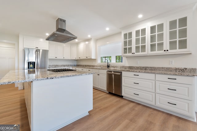 kitchen with island range hood, a center island, white cabinets, light wood-type flooring, and appliances with stainless steel finishes