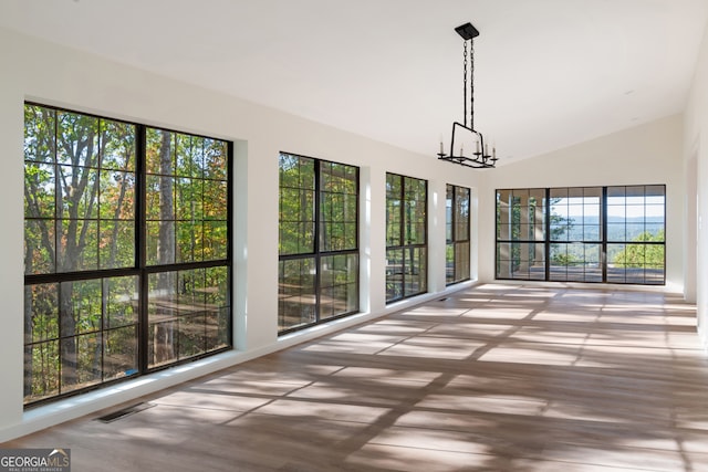 unfurnished sunroom with an inviting chandelier, plenty of natural light, and vaulted ceiling