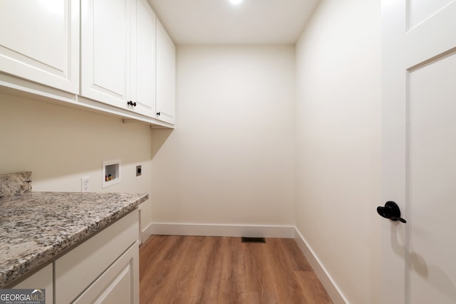 clothes washing area with hookup for an electric dryer, hookup for a washing machine, light hardwood / wood-style floors, and cabinets