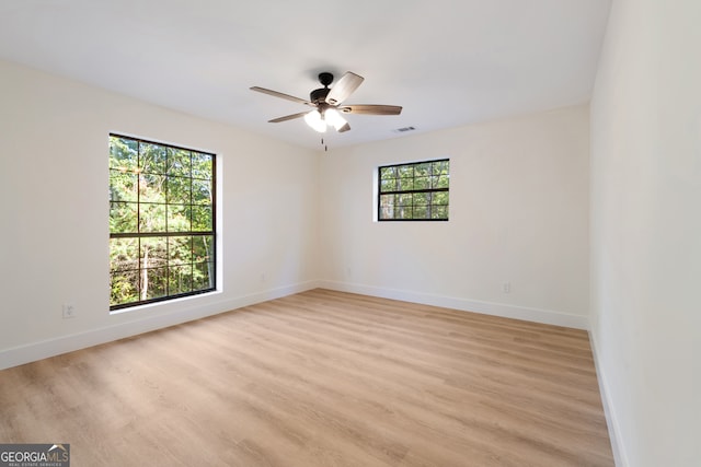 empty room with light hardwood / wood-style flooring, a healthy amount of sunlight, and ceiling fan