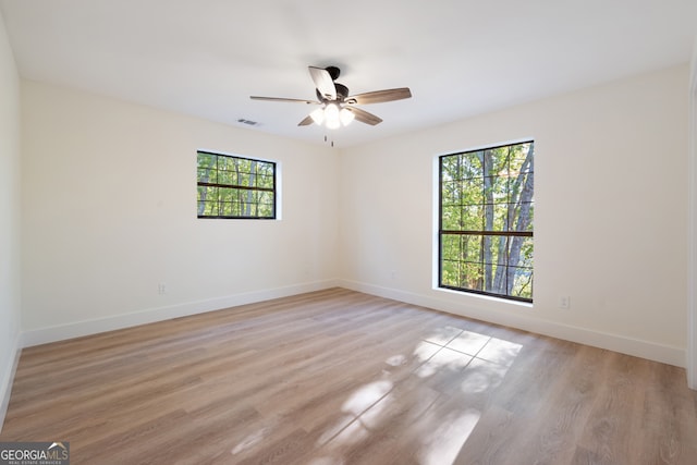 spare room with light hardwood / wood-style flooring, a healthy amount of sunlight, and ceiling fan