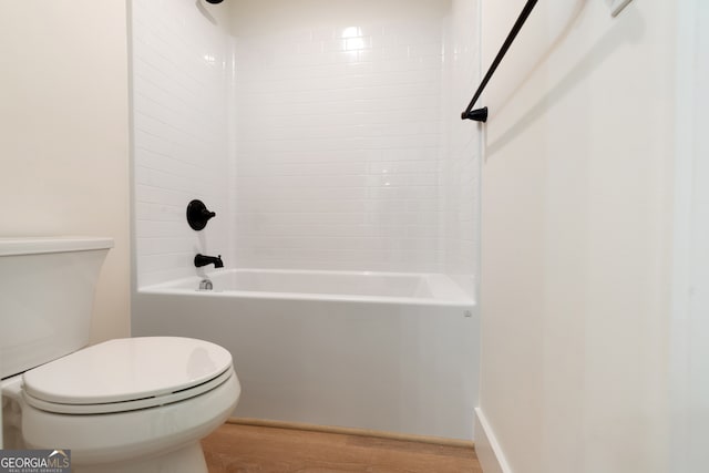 bathroom with toilet, wood-type flooring, and tiled shower / bath