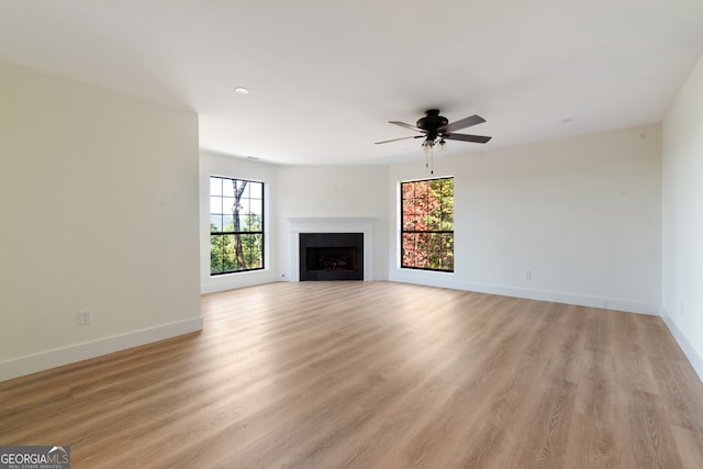 unfurnished living room featuring a wealth of natural light, light hardwood / wood-style flooring, and ceiling fan