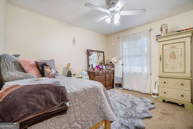 carpeted bedroom featuring ceiling fan and a textured ceiling