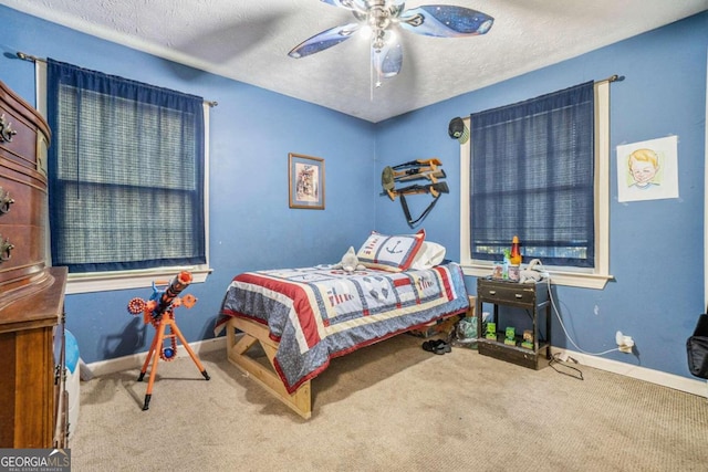 carpeted bedroom featuring ceiling fan and a textured ceiling