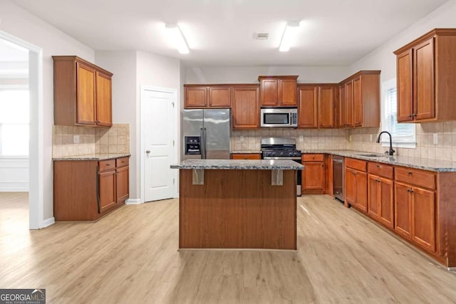 kitchen featuring light stone counters, sink, appliances with stainless steel finishes, and light hardwood / wood-style floors