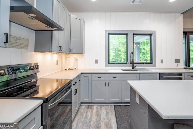 kitchen with stainless steel appliances, plenty of natural light, wall chimney exhaust hood, and light wood-type flooring