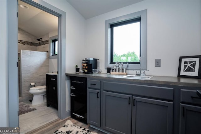 bathroom with vanity, toilet, hardwood / wood-style floors, a shower, and vaulted ceiling