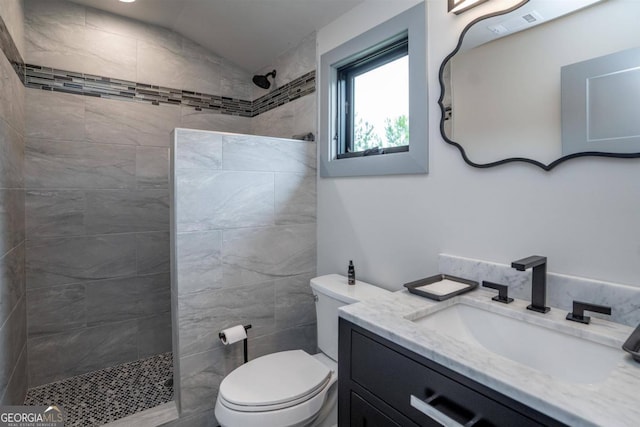 bathroom with lofted ceiling, a tile shower, toilet, and vanity