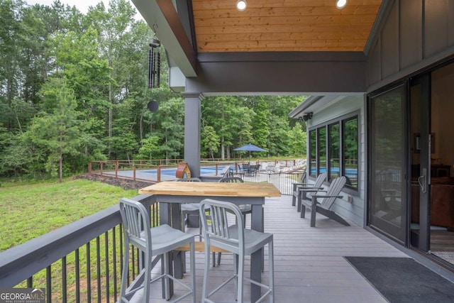 wooden terrace featuring a pool and a lawn