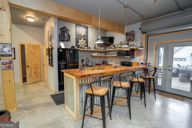 bar with pendant lighting, black appliances, sink, and wood counters