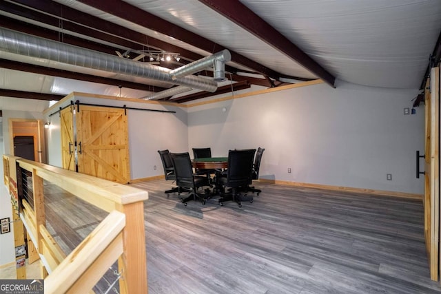 dining room featuring a barn door, wood-type flooring, and beam ceiling