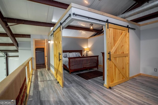 bedroom with lofted ceiling with beams, a barn door, and dark wood-type flooring