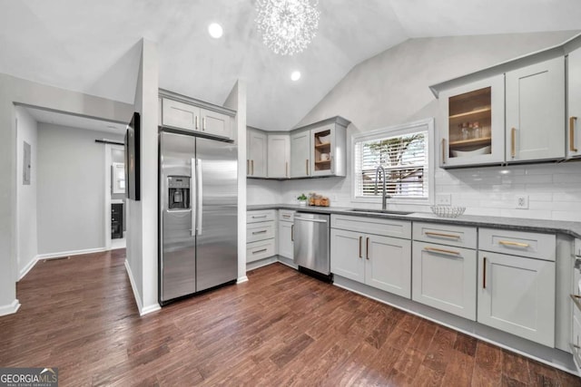 kitchen featuring lofted ceiling, sink, gray cabinetry, dark wood-type flooring, and appliances with stainless steel finishes