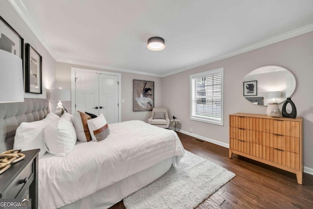 bedroom with a closet, dark hardwood / wood-style floors, and crown molding