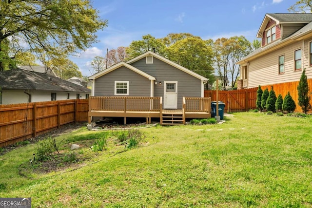 rear view of house with a wooden deck and a lawn