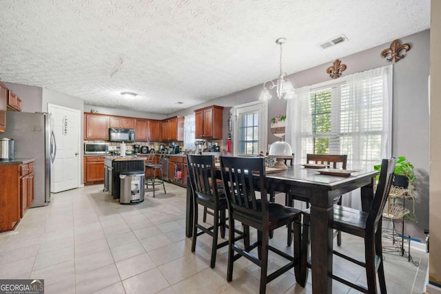 tiled dining area with a chandelier and a textured ceiling