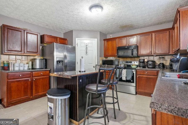 kitchen with tasteful backsplash, a breakfast bar area, appliances with stainless steel finishes, and a kitchen island