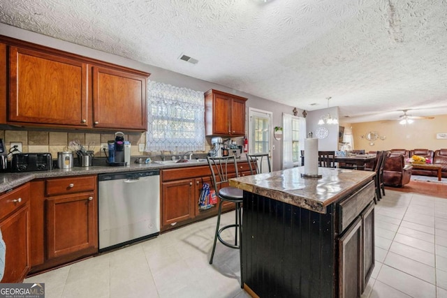 kitchen with ceiling fan, tasteful backsplash, dishwasher, a center island, and a textured ceiling