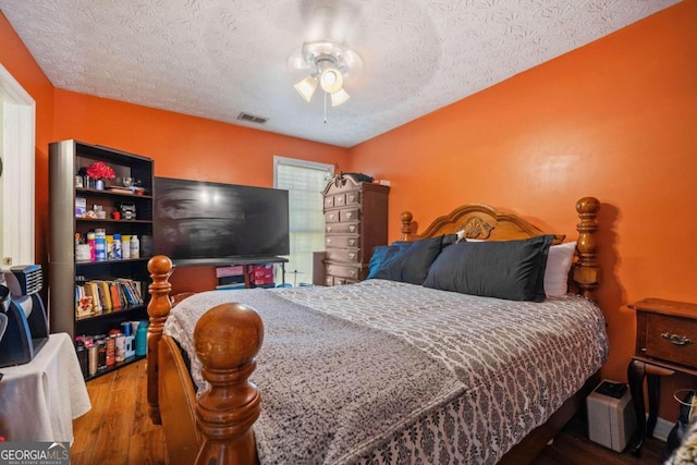 bedroom with ceiling fan, wood-type flooring, and a textured ceiling