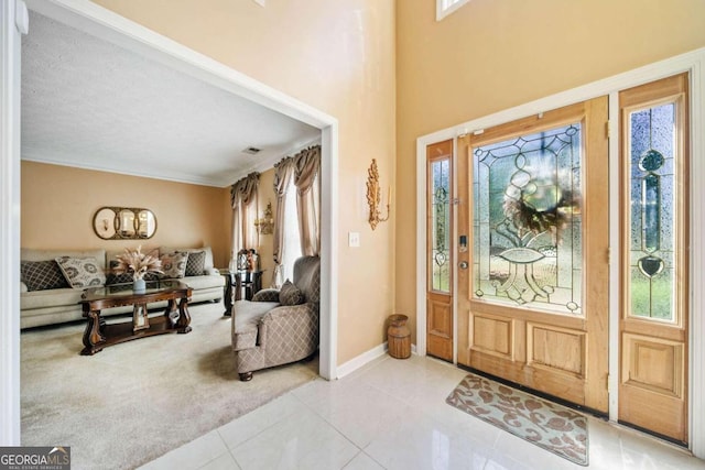 entrance foyer with ornamental molding, a textured ceiling, and light tile patterned floors