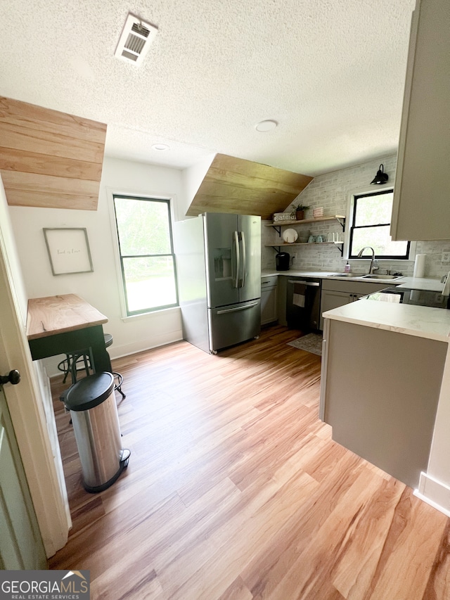 kitchen featuring light wood-type flooring, gray cabinetry, a textured ceiling, stainless steel appliances, and sink