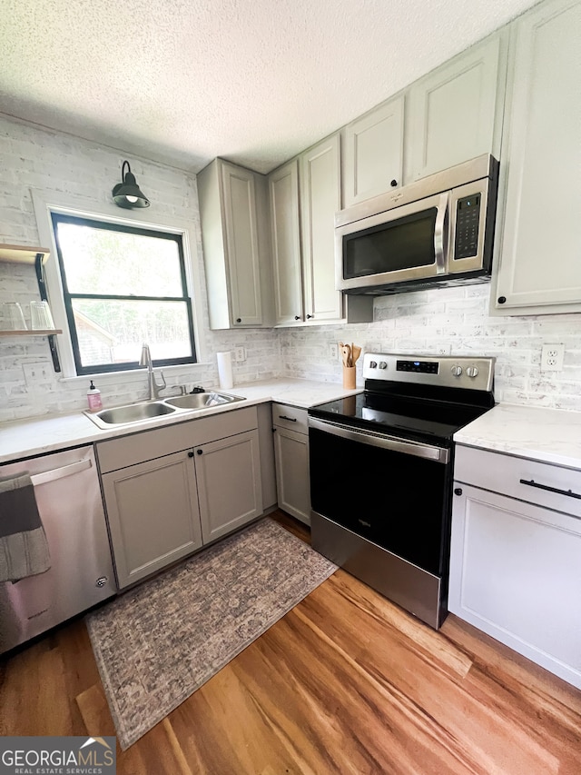 kitchen featuring a textured ceiling, light hardwood / wood-style floors, sink, and stainless steel appliances