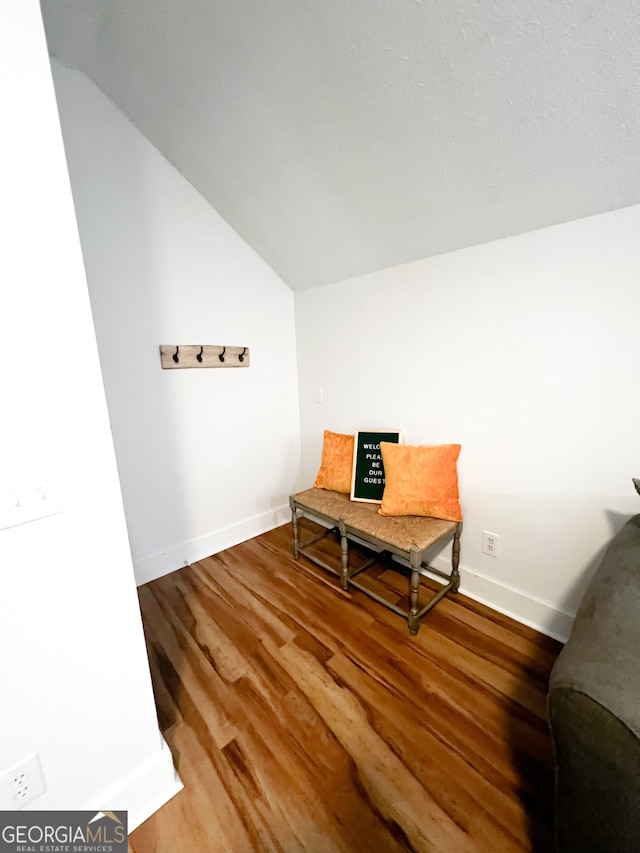 sitting room featuring wood-type flooring and vaulted ceiling