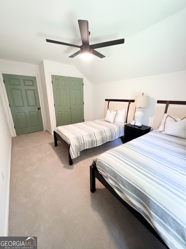 bedroom with ceiling fan, a closet, light colored carpet, and vaulted ceiling