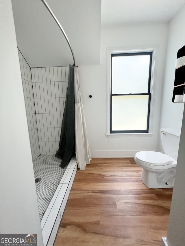 bathroom with wood-type flooring, toilet, and walk in shower