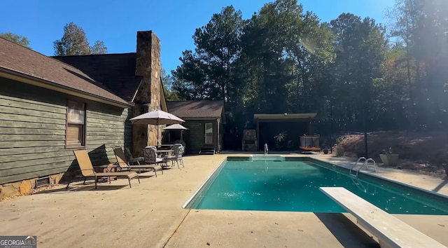 view of swimming pool with a diving board and a patio area