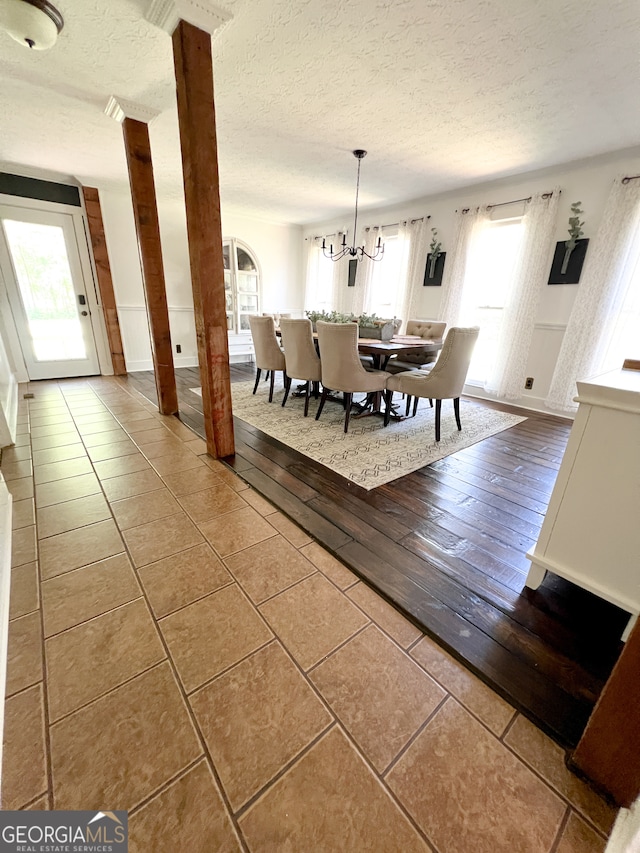 unfurnished dining area featuring a textured ceiling, hardwood / wood-style flooring, and an inviting chandelier