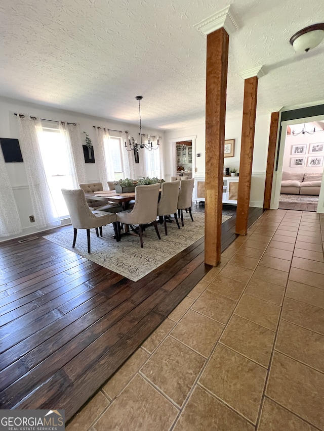 tiled dining area with a textured ceiling and a chandelier