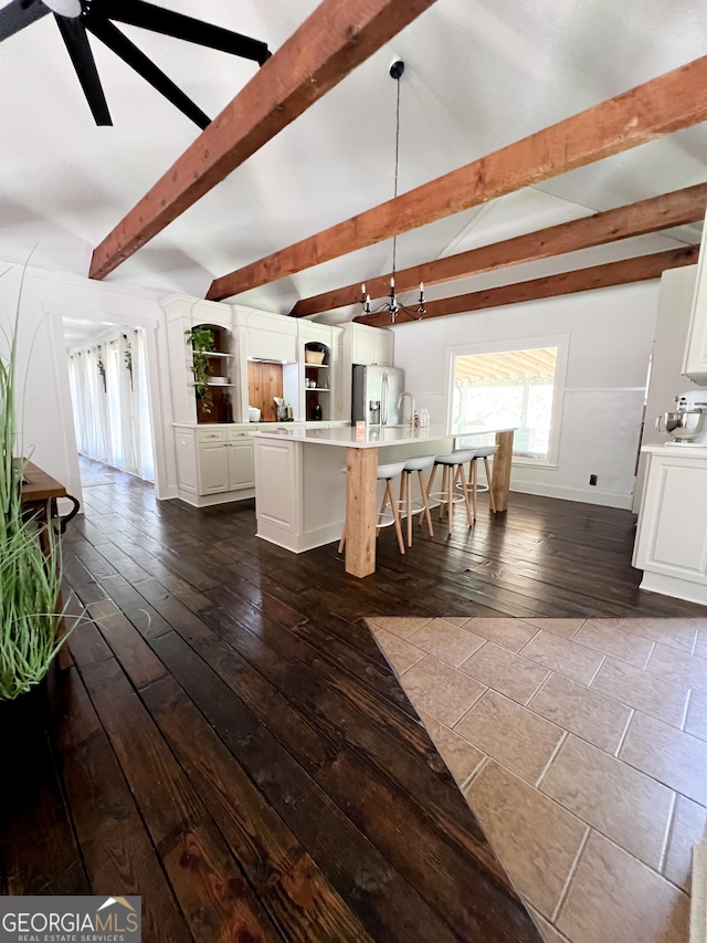 unfurnished dining area with ceiling fan, beamed ceiling, and dark wood-type flooring