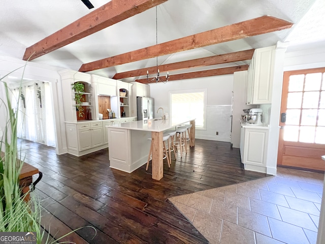 kitchen featuring white cabinetry, sink, dark hardwood / wood-style flooring, decorative light fixtures, and a kitchen island with sink