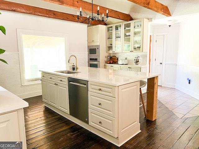 kitchen with stainless steel appliances, sink, a center island with sink, beamed ceiling, and dark hardwood / wood-style floors