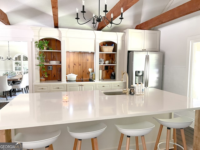 kitchen with stainless steel refrigerator with ice dispenser, an inviting chandelier, a spacious island, and sink