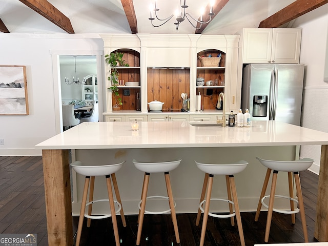 kitchen featuring a breakfast bar, sink, stainless steel fridge, beamed ceiling, and a chandelier