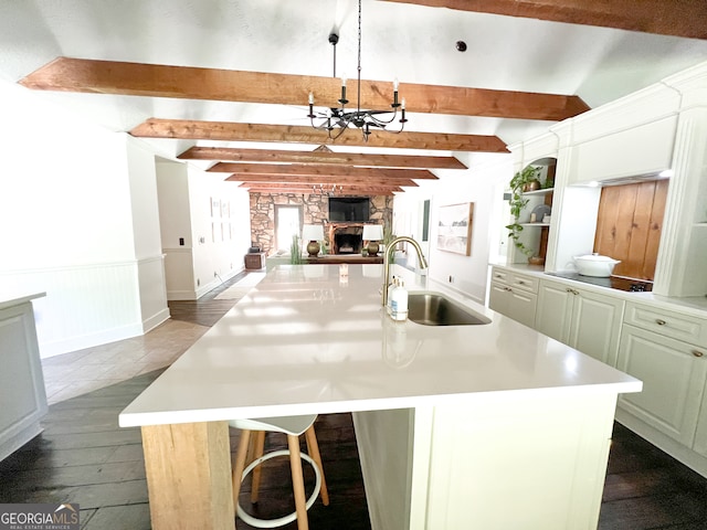 kitchen featuring pendant lighting, a kitchen island with sink, sink, a breakfast bar area, and a chandelier