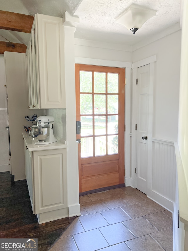 doorway to outside featuring light tile patterned floors and a textured ceiling